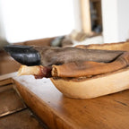Eine Holzschale steht auf einem Holztisch und darin sind 3 Snacks zu sehen, einmal die Rinderkopfhaut, einmal die Entenbruststange und ein Hirschunterbein um die Größen deutlich zu erkennen. 