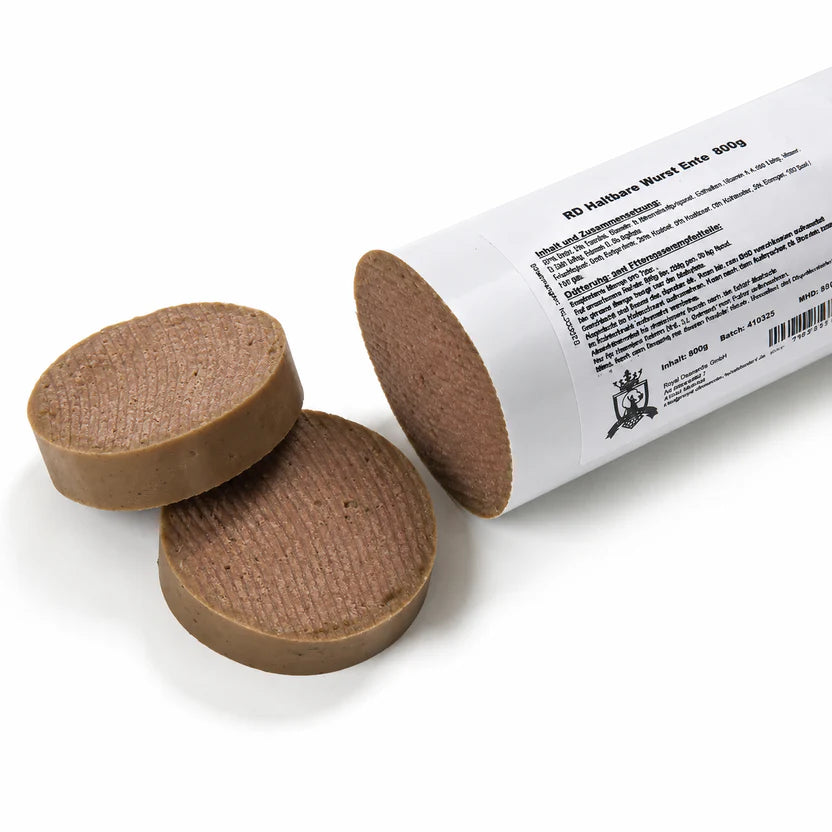 Eine angeschnittene haltbare Entewurst für Hunde (200 g) liegt auf einem weißen Hintergrund. Das abgeschnittene Endstück ist neben der geöffneten Wurst platziert und zeigt die glatte, schnittfeste Struktur. Ein weicher, natürlicher Schatten sorgt für eine realistische Produktdarstellung.