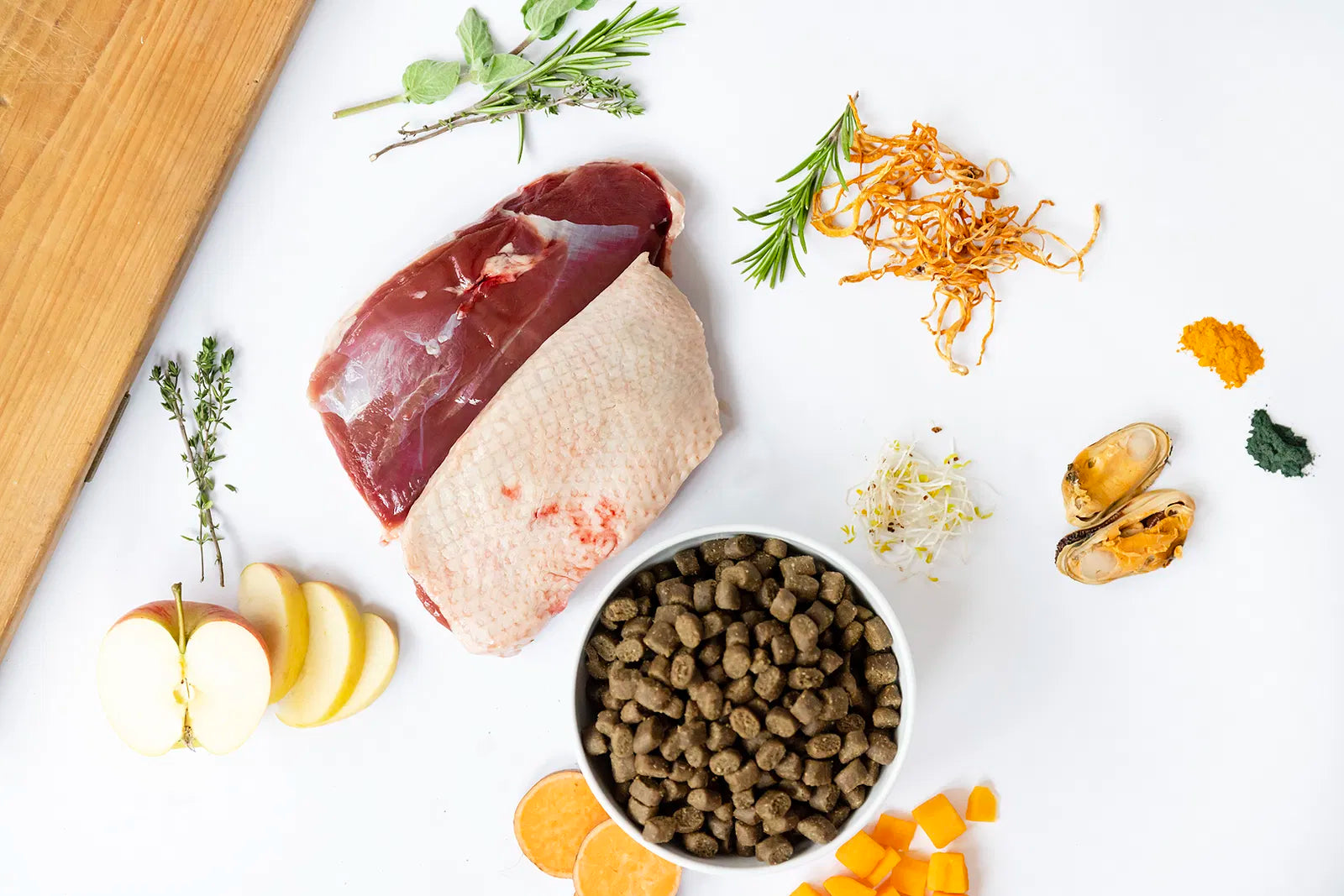 YDOLO Ente Semi-Moist Hundefutter im Napf vor weißem Hintergrund. Dazu die frischen Zutaten. Halbfeuchtes, getreide- und glutenfreies Hundefutter mit 75 % Frischfleisch, Monoprotein und präbiotischen Kräutern – geeignet für Hunde jeder Rasse.
